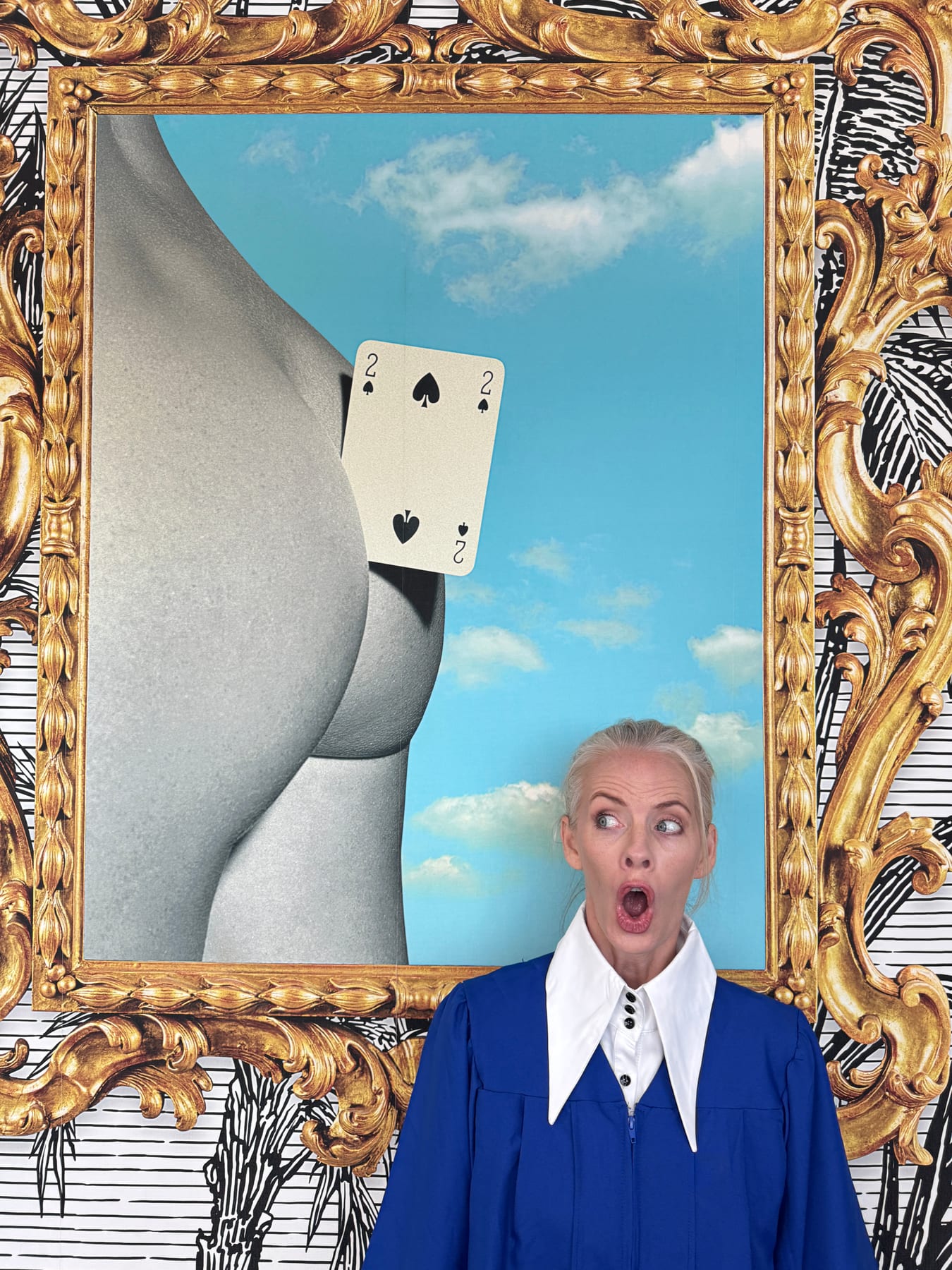 Janelle in a blue outfit making a surprised face beside a playfully framed artwork