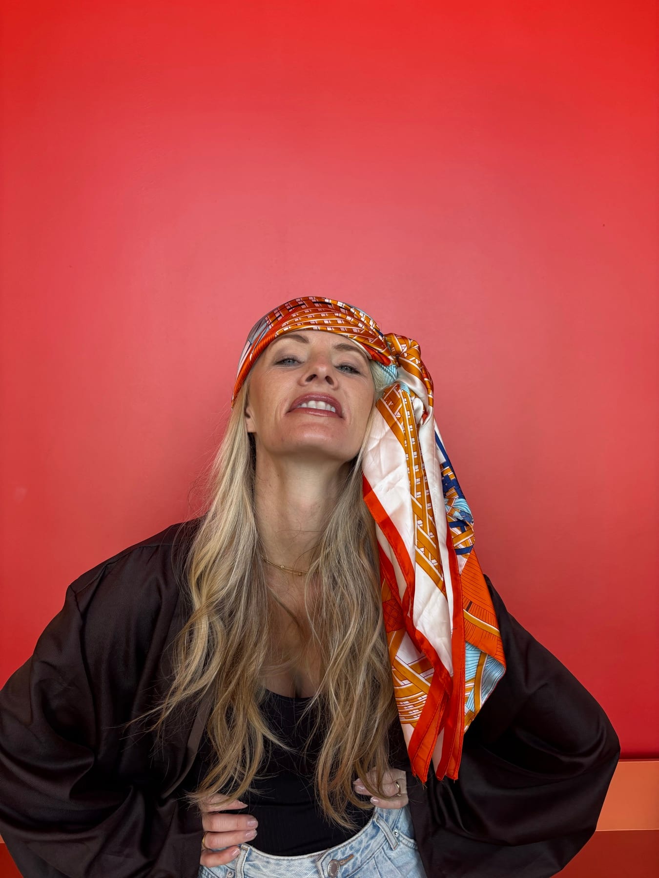 Janelle wearing a patterned headscarf against a vivid red wall