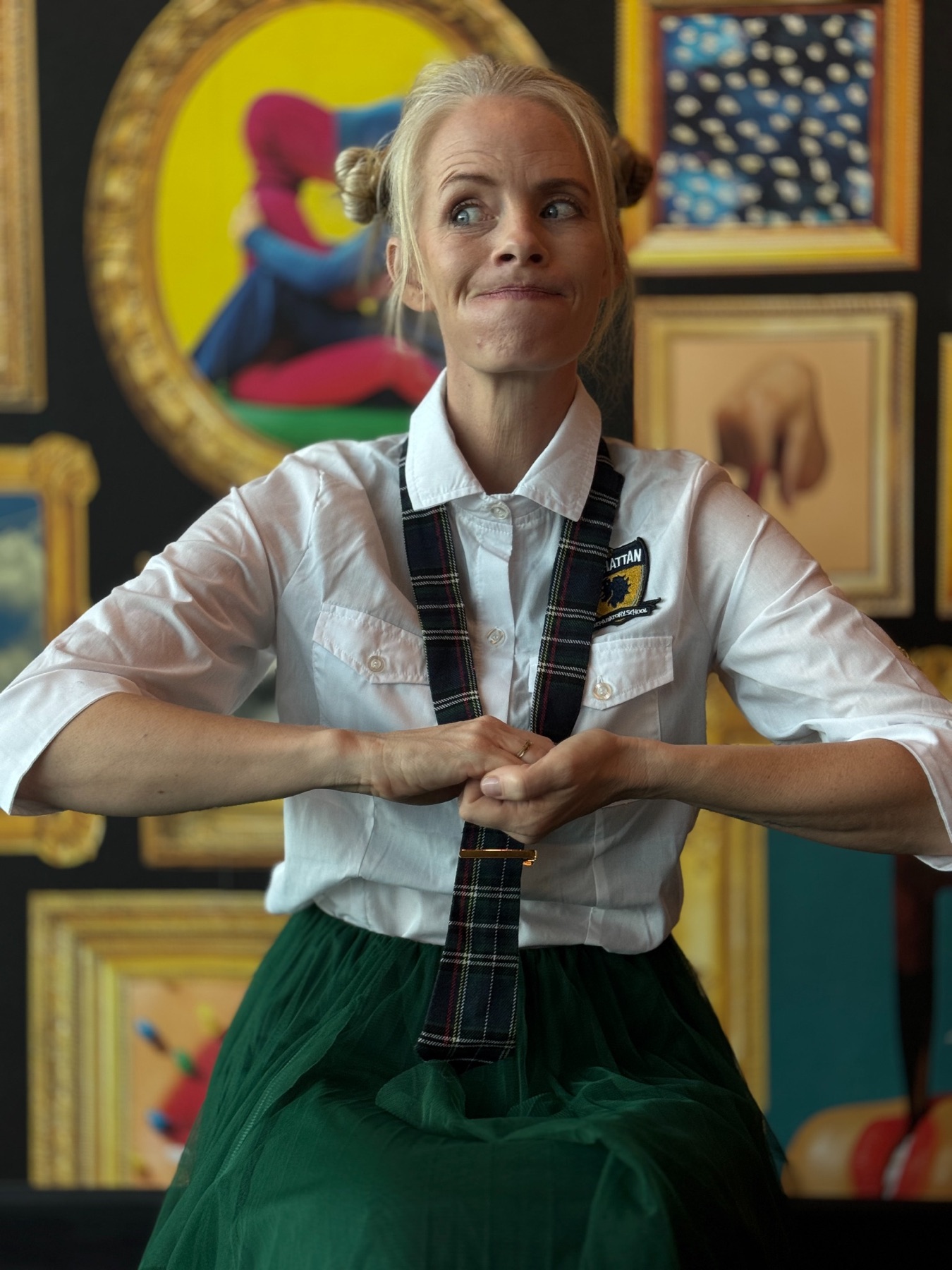 Janelle smiling in a shirt and tie in a colourful art gallery