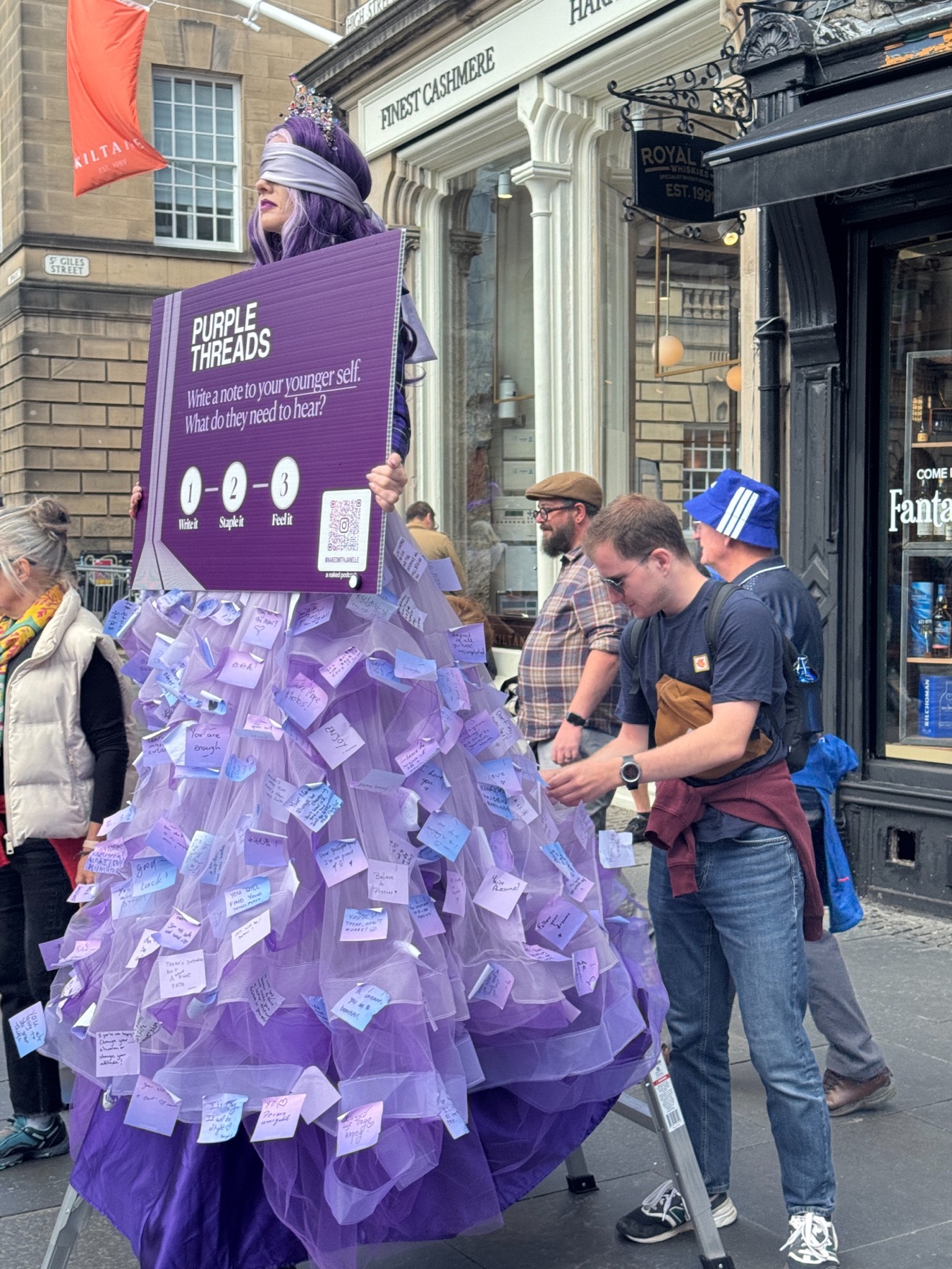 Janelle holding the Purple Threads prompt while a visitor adds a note